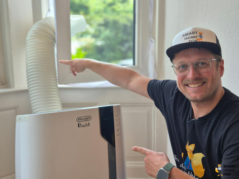 Im Fokus steht eine mobile Klimaanlage mit klassischem Abluftschlauch.